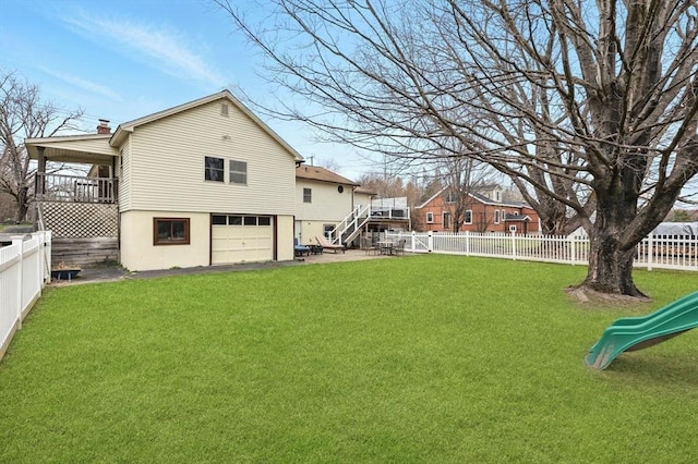 rear view of house featuring an attached garage, a fenced backyard, a lawn, and stucco siding