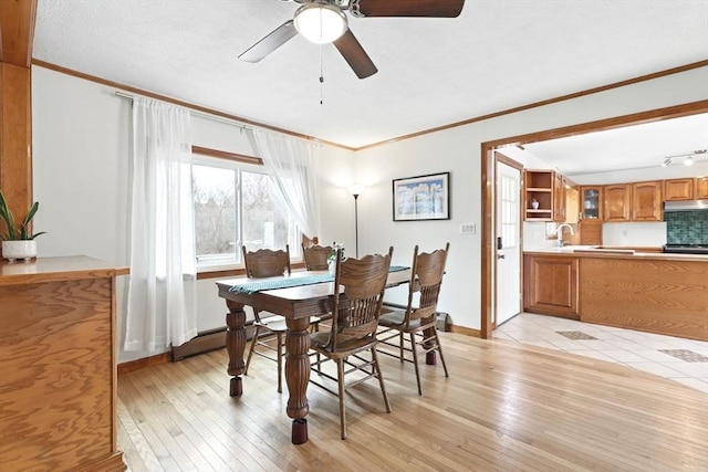 dining space featuring crown molding, a ceiling fan, baseboards, and light wood-type flooring