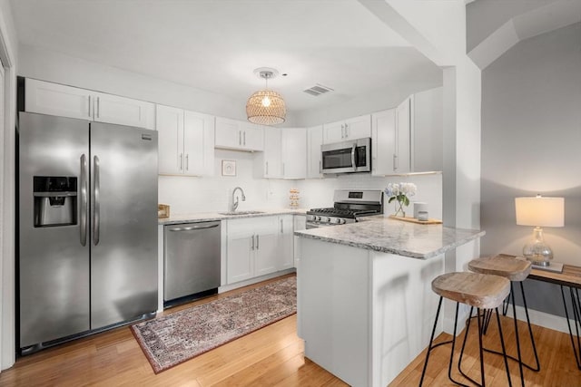 7 S Stone Mill Dr Unit 403, Dedham, MA 02026 - kitchen featuring appliances with stainless steel finishes, a sink, a peninsula, and light stone countertops