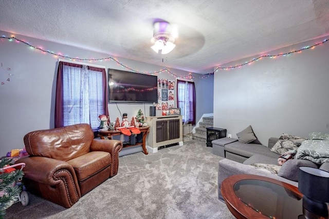 living room featuring ceiling fan, light colored carpet, a textured ceiling, and a wealth of natural light