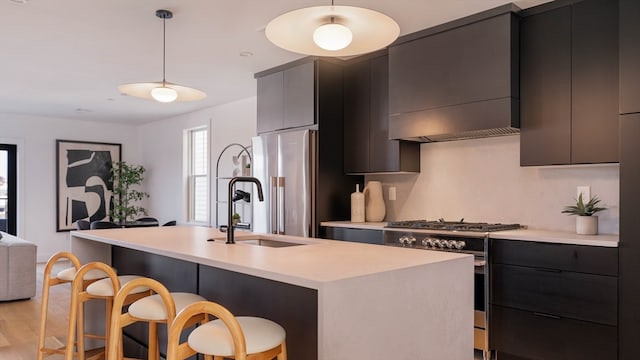 kitchen featuring a center island with sink, hanging light fixtures, a breakfast bar area, light hardwood / wood-style flooring, and stainless steel appliances