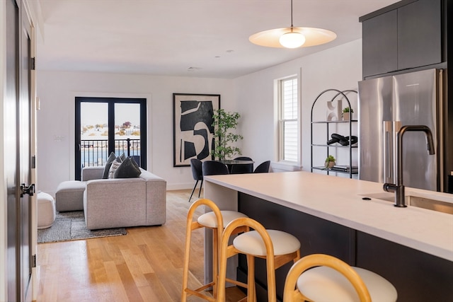 kitchen featuring decorative light fixtures, light hardwood / wood-style floors, plenty of natural light, and high quality fridge