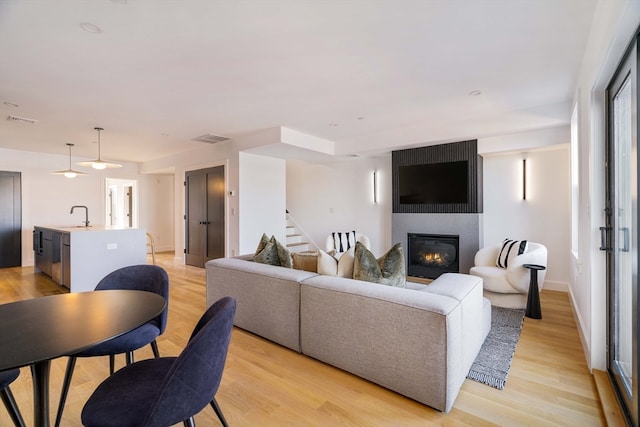 living room with a fireplace, light hardwood / wood-style floors, and sink