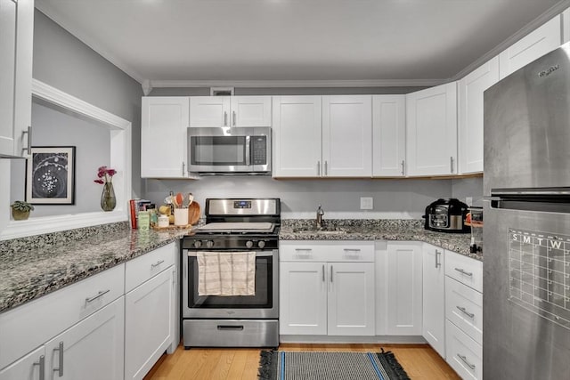 32 Juniper St Unit 91, Brookline, MA 02445 - kitchen with stainless steel appliances, white cabinetry, light wood-style floors, and dark stone counters
