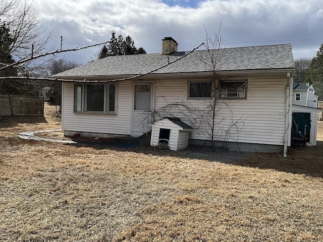 rear view of property with a shingled roof, a chimney, and fence