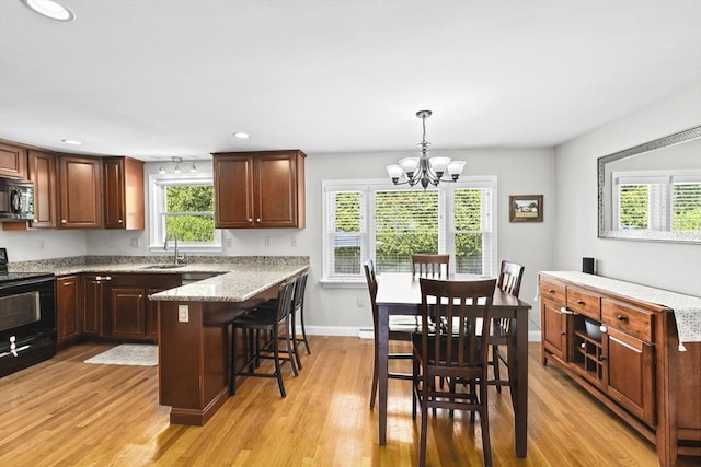 58 Spring St, Weymouth, MA 02188 - kitchen featuring black appliances, a breakfast bar, a sink, light wood-type flooring, and baseboards