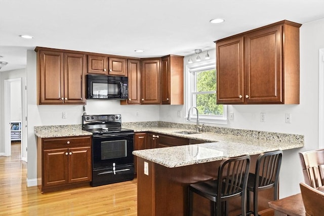 58 Spring St, Weymouth, MA 02188 - kitchen featuring black appliances, a sink, a peninsula, light wood-style flooring, and a breakfast bar area