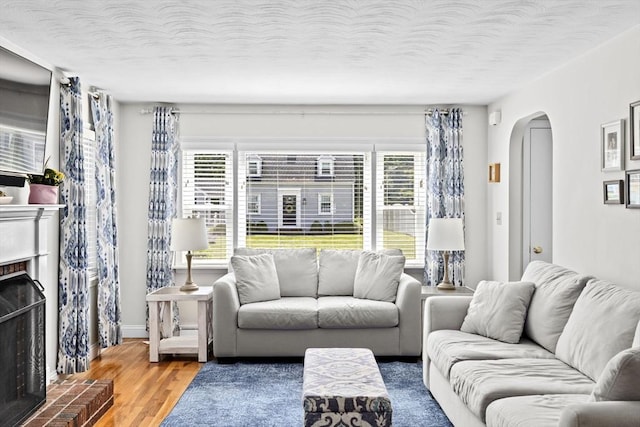58 Spring St, Weymouth, MA 02188 - living area featuring arched walkways, a fireplace with raised hearth, healthy amount of natural light, wood finished floors, and a textured ceiling