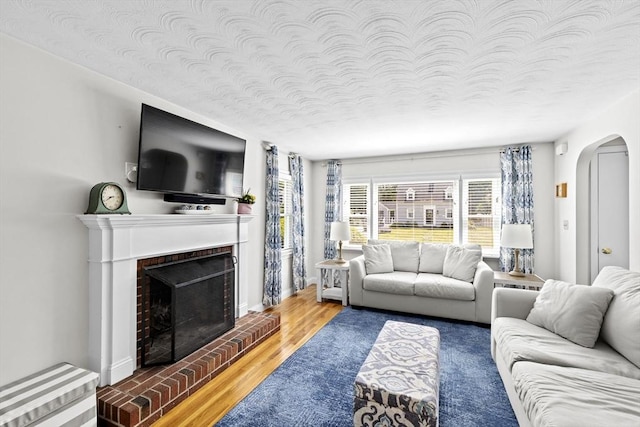 58 Spring St, Weymouth, MA 02188 - living area with arched walkways, wood finished floors, a fireplace, and a textured ceiling