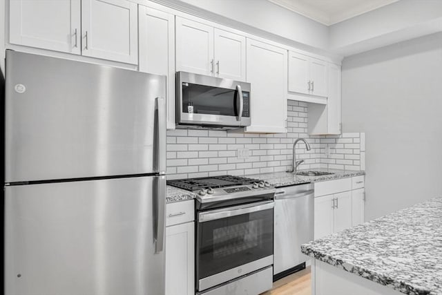 kitchen featuring white cabinetry, stainless steel appliances, light stone countertops, and sink