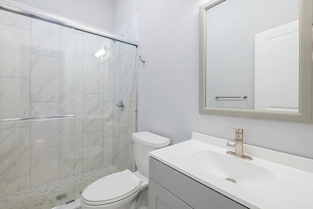 bathroom featuring vanity, a shower with shower door, and toilet