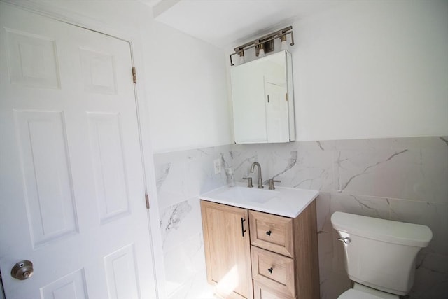 half bathroom featuring tile walls, vanity, and toilet
