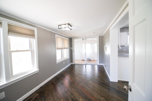 empty room featuring baseboards, wood finished floors, and crown molding