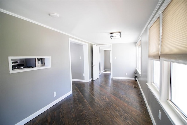 empty room with wood finished floors, baseboards, and ornamental molding