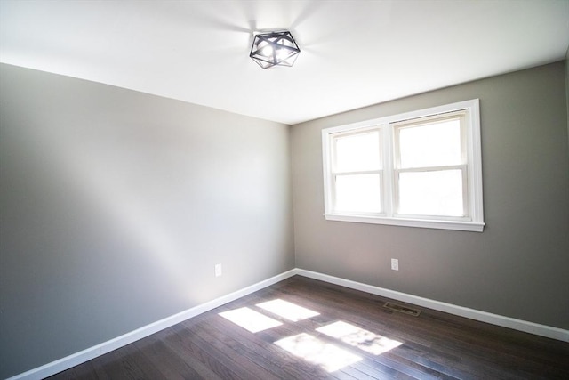empty room featuring dark wood-type flooring and baseboards