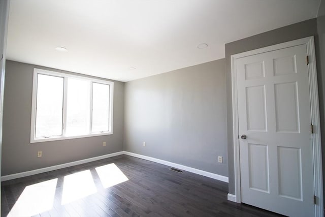 spare room featuring baseboards and dark wood-style flooring