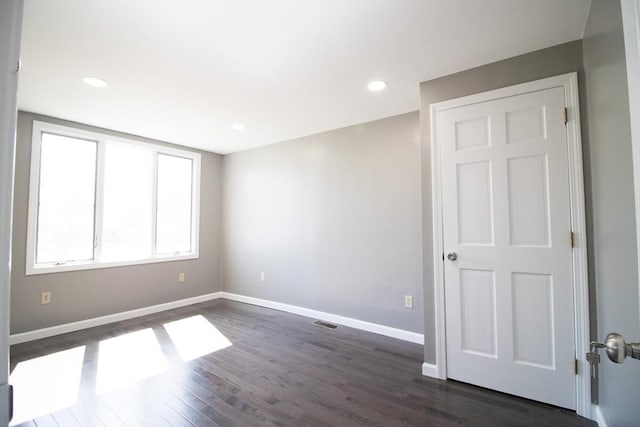 empty room with dark wood finished floors, baseboards, and recessed lighting
