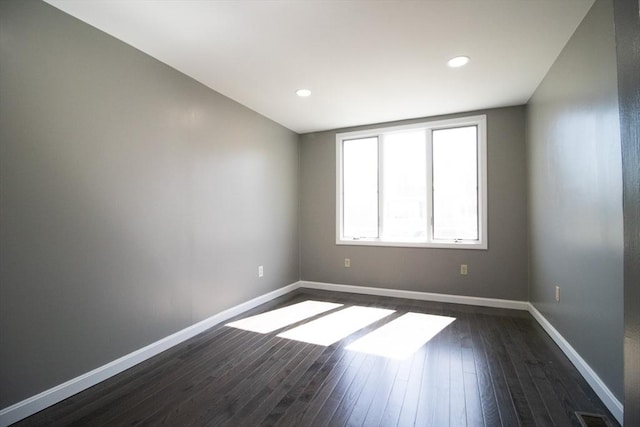 spare room with dark wood-style flooring, baseboards, and recessed lighting
