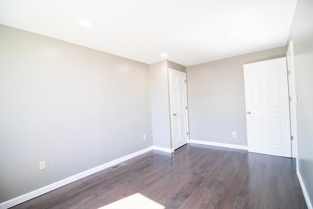 empty room with dark wood-style floors, baseboards, and recessed lighting
