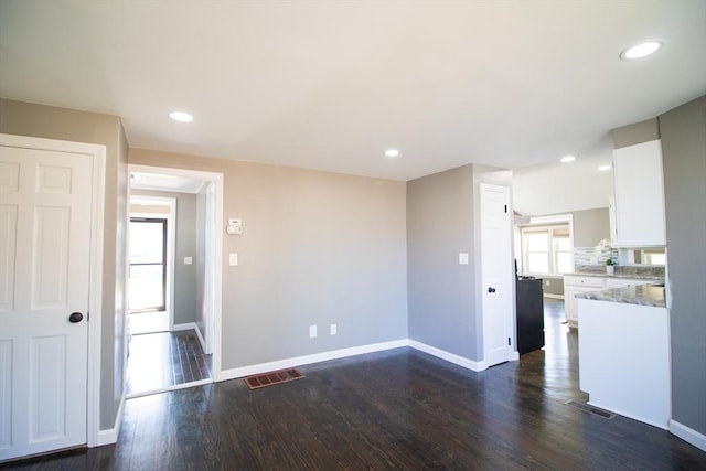 unfurnished living room featuring baseboards, dark wood finished floors, and recessed lighting