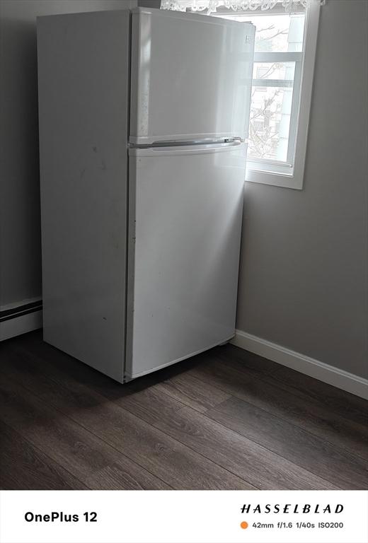 54 Shirley Ave, Revere, MA 02151 - unfurnished bedroom with freestanding refrigerator, dark wood finished floors, a baseboard radiator, and baseboards