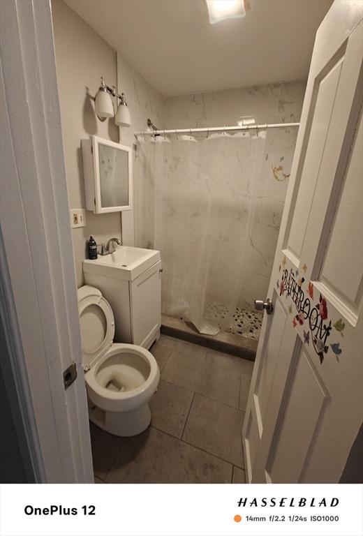 54 Shirley Ave, Revere, MA 02151 - bathroom featuring a shower stall, a sink, tile patterned floors, and toilet
