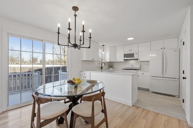 kitchen featuring sink, white cabinetry, pendant lighting, and white appliances