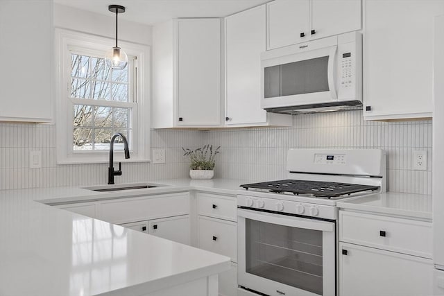 kitchen featuring pendant lighting, white appliances, white cabinets, sink, and backsplash