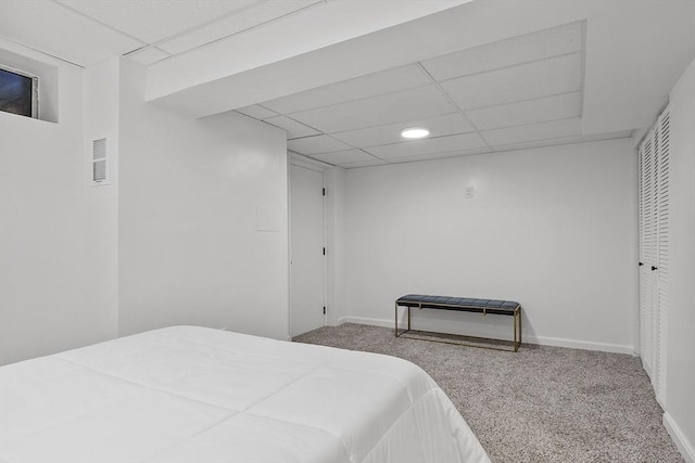 carpeted bedroom with a drop ceiling and a closet