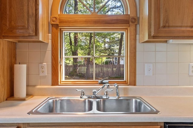15 Moore Rd, Westford, MA 01886 - kitchen featuring a sink, light countertops, brown cabinets, and decorative backsplash