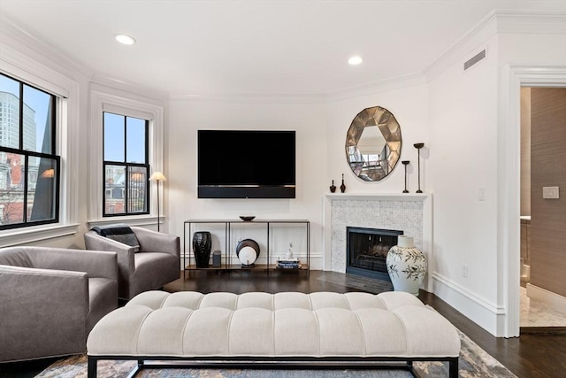 living room featuring dark hardwood / wood-style flooring, ornamental molding, and a tile fireplace