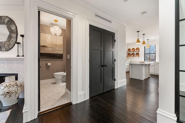 corridor with ornamental molding and dark hardwood / wood-style floors