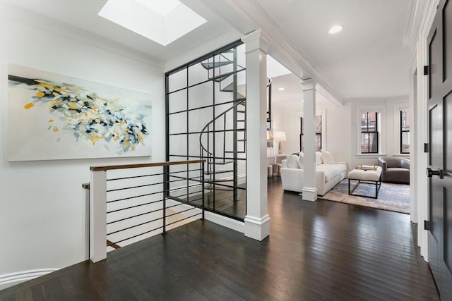 hall featuring a skylight, crown molding, dark wood-type flooring, and decorative columns