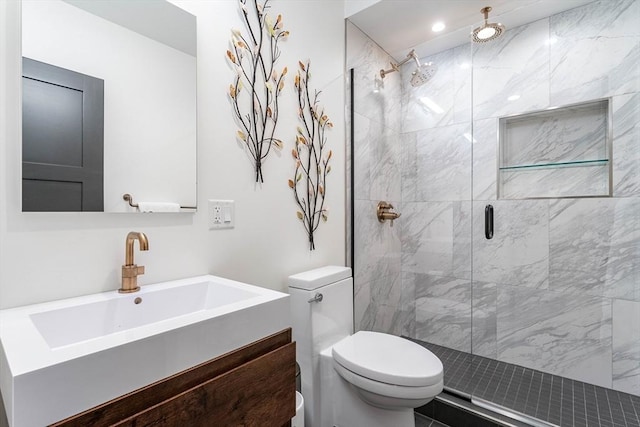 bathroom featuring vanity, a shower with door, and toilet