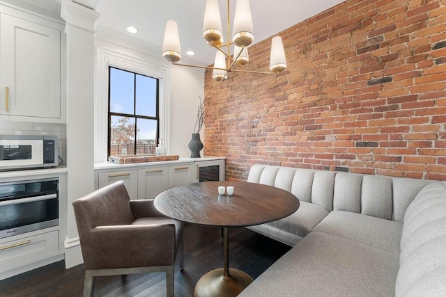 dining area with brick wall, dark hardwood / wood-style floors, and a notable chandelier