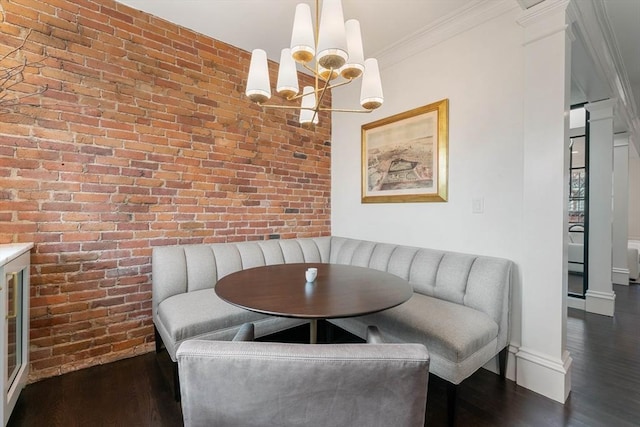 dining area with dark hardwood / wood-style flooring, an inviting chandelier, ornamental molding, brick wall, and breakfast area