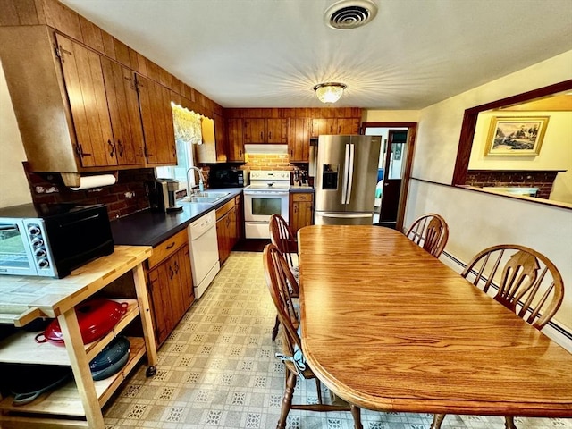 43 Shirley Ave, Methuen, MA 01844 - kitchen featuring white appliances, under cabinet range hood, brown cabinetry, dark countertops, and light floors
