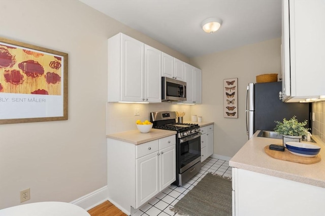 854 Massachusetts Ave Unit 11, Cambridge, MA 02139 - kitchen with stainless steel appliances, decorative backsplash, white cabinets, light countertops, and light tile patterned floors