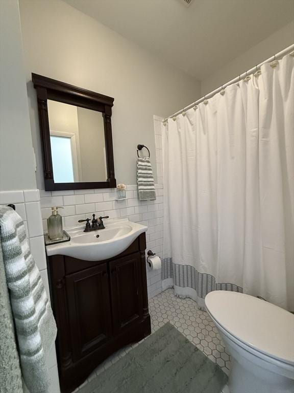 full bathroom featuring toilet, vanity, tile patterned floors, tile walls, and a shower with curtain