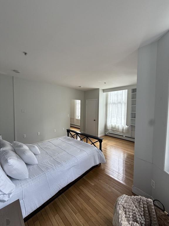 bedroom featuring a baseboard heating unit and wood-type flooring