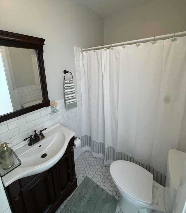 bathroom with toilet, vanity, tile walls, a shower with shower curtain, and tile patterned floors
