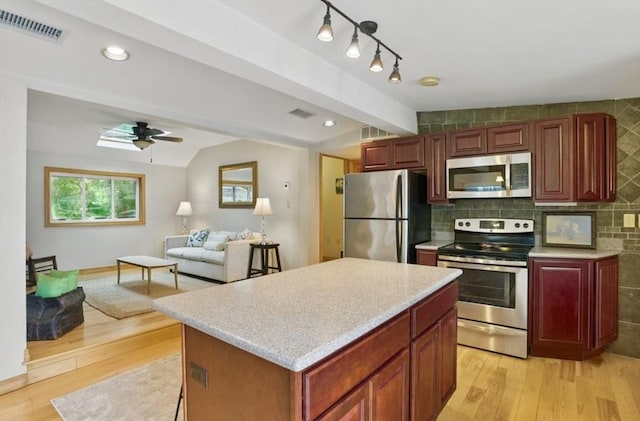 kitchen featuring appliances with stainless steel finishes, lofted ceiling, light countertops, light wood-type flooring, and ceiling fan