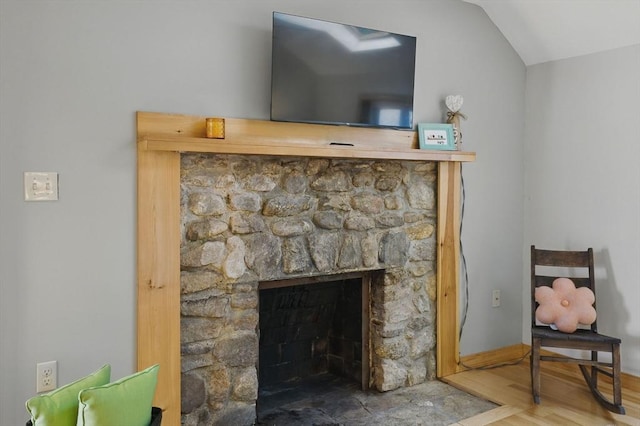 detailed view of a fireplace, baseboards, and wood finished floors