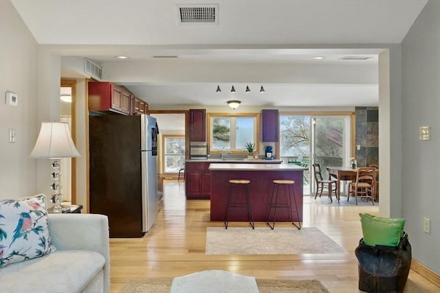 kitchen featuring freestanding refrigerator, dark brown cabinets, and light wood finished floors