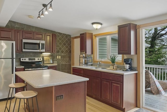 kitchen featuring appliances with stainless steel finishes, rail lighting, light countertops, a sink, and light wood finished floors