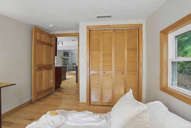 bedroom with a closet, light wood-style floors, and baseboards