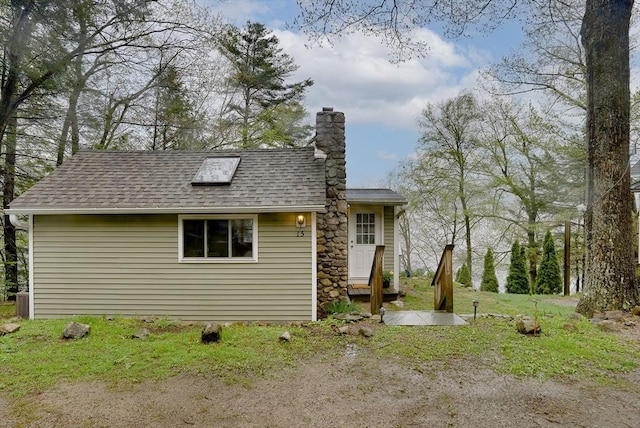 back of property featuring a shingled roof and a chimney