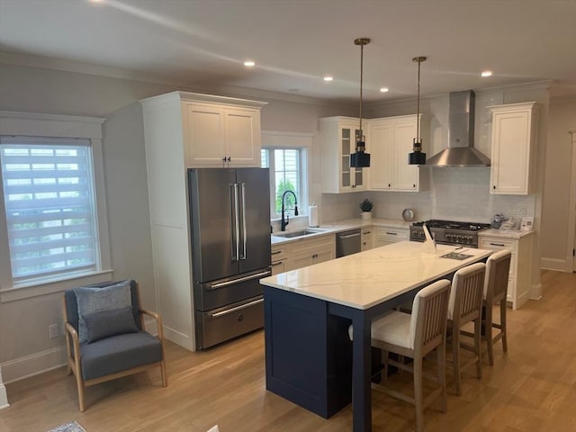 255 Old Main Rd Unit 2A, Falmouth, MA 02556 - kitchen with high end appliances, wall chimney exhaust hood, white cabinetry, light wood-type flooring, and ornamental molding