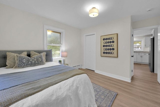 195 Pompeo Rd, Thompson, CT 06255 - bedroom featuring a baseboard heating unit, multiple windows, light wood-style floors, and freestanding refrigerator