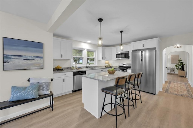 195 Pompeo Rd, Thompson, CT 06255 - kitchen featuring appliances with stainless steel finishes, light wood-type flooring, arched walkways, a breakfast bar, and white cabinets
